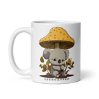 A white ceramic mug with a illustration of a koala bear under a golden mushroom with a 'SHROOMEEF' text on the front.